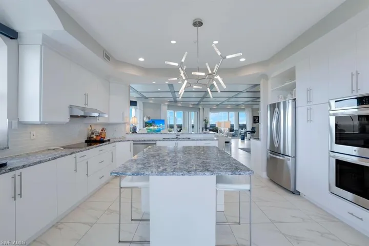 Kitchen featuring appliances with stainless steel finishes, white cabinets, a kitchen island, a breakfast bar area, and an inviting chandelier
