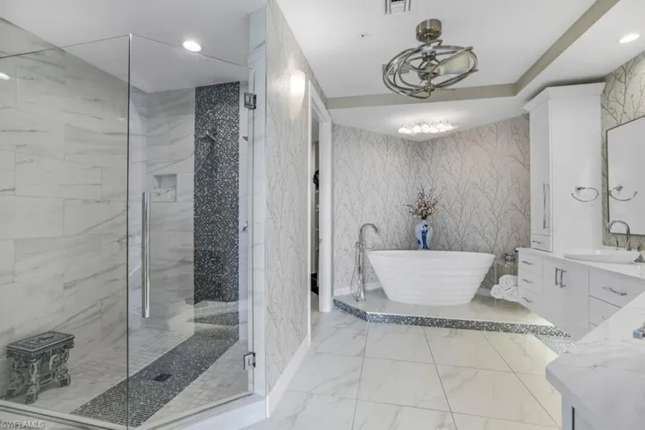 Bathroom featuring an inviting chandelier, vanity, and shower with separate bathtub