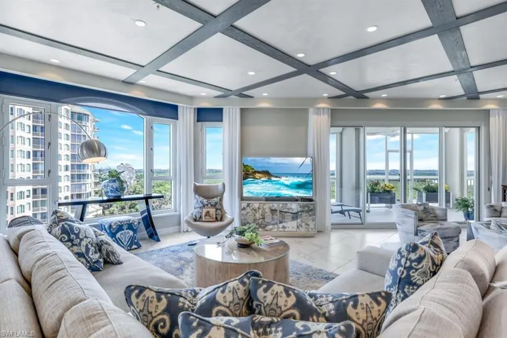 Living room with beam ceiling, coffered ceiling, and light tile patterned floors