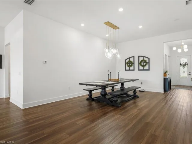 Dining space featuring baseboards, visible vents, a notable chandelier, and dark wood finished floors