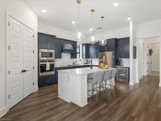 Kitchen with beverage cooler, light countertops, a sink, tasteful backsplash, and appliances with stainless steel finishes