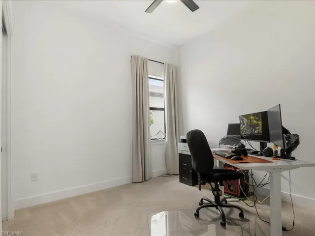 Office area featuring light carpet, baseboards, and ceiling fan