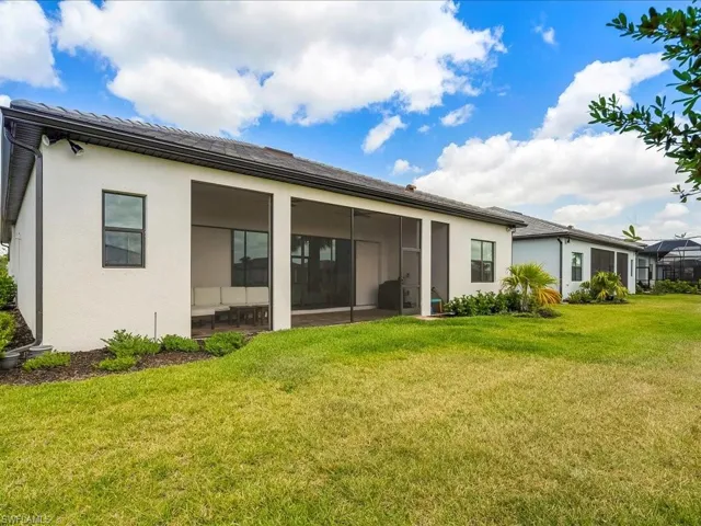 Rear view of property featuring a sunroom, stucco siding, and a lawn