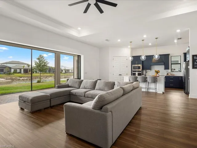 Living room with recessed lighting, ornamental molding, ceiling fan, dark wood-type flooring, and a raised ceiling