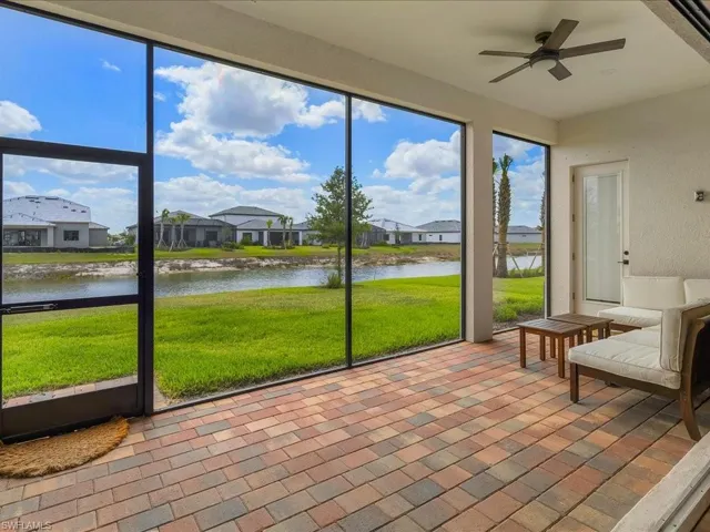Sunroom / solarium featuring a residential view, a ceiling fan, and a water view