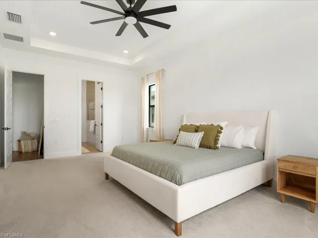 Bedroom featuring light colored carpet, a raised ceiling, visible vents, and recessed lighting