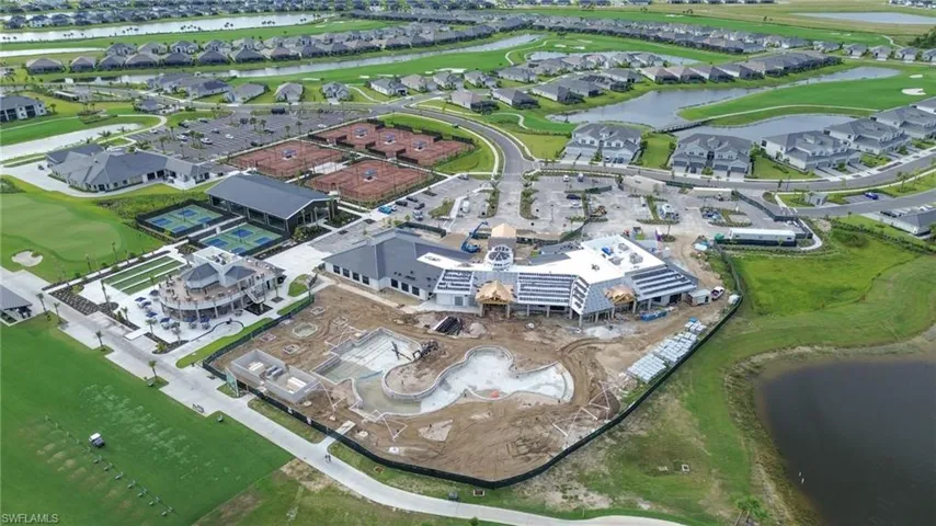 Community aerial featuring a golf course, multiple tennis courts, pickleball courts, and a large central building with a pool area under construction