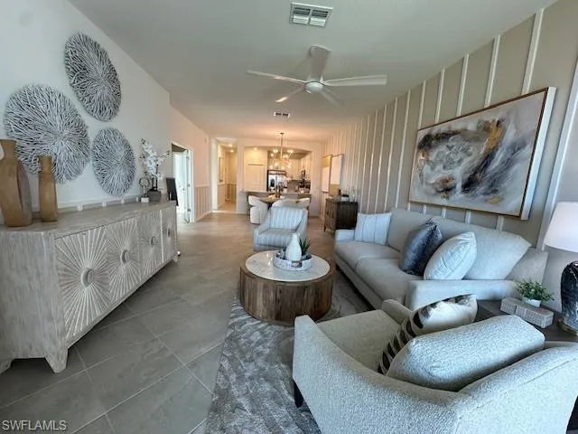 Living room with a ceiling fan, a decorative wall, and a chandelier