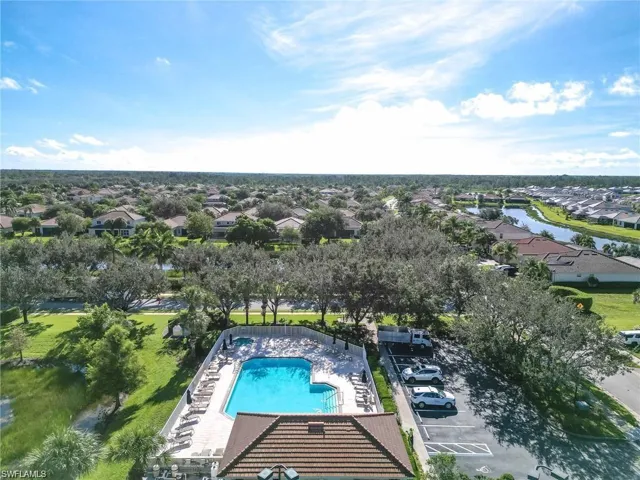 Aerial perspective of suburban area featuring a pool area and a nearby body of water