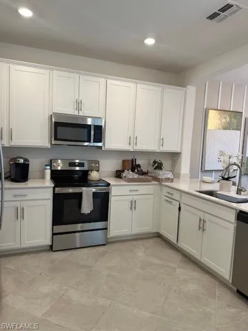 Kitchen with stainless steel range oven, white cabinets, recessed lighting, dishwasher, and light stone countertops