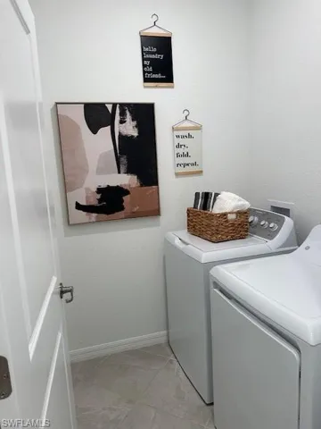Laundry room featuring washing machine and dryer, a textured wall, and light tile patterned flooring