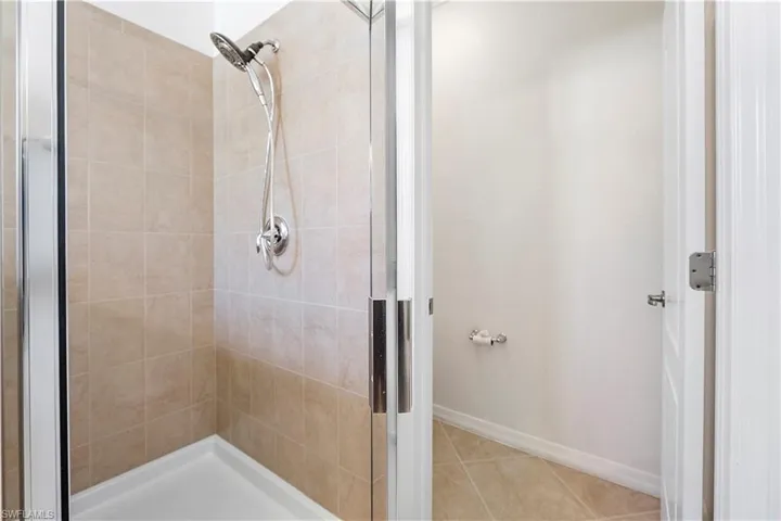 Bathroom with tile patterned flooring, a shower stall, and baseboards