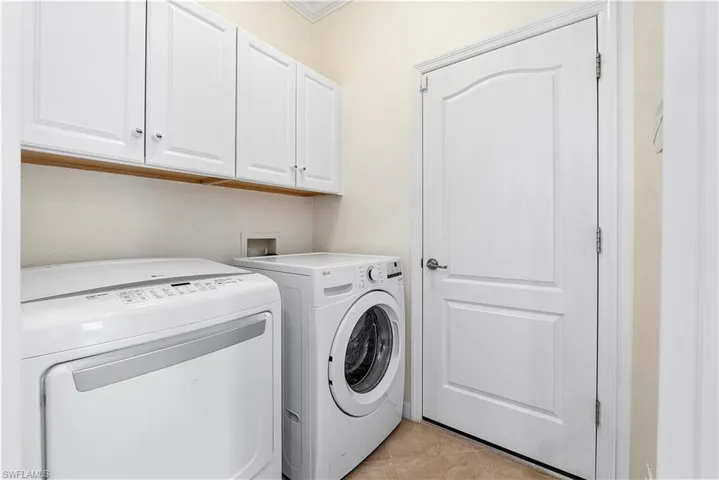 Washroom with light tile patterned floors, cabinet space, and washing machine and dryer