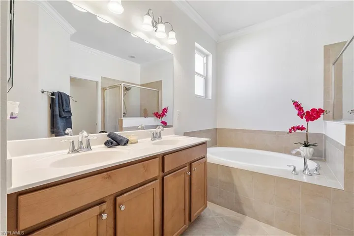 Full bathroom featuring a garden tub, a sink, tile patterned flooring, a shower stall, and crown molding