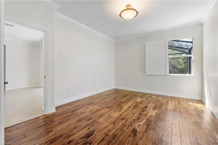 Unfurnished room with hardwood / wood-style floors, baseboards, visible vents, and ornamental molding