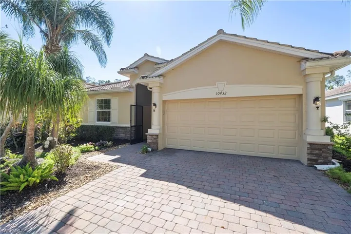 View of front of property with a garage, decorative driveway, stone siding, and stucco siding