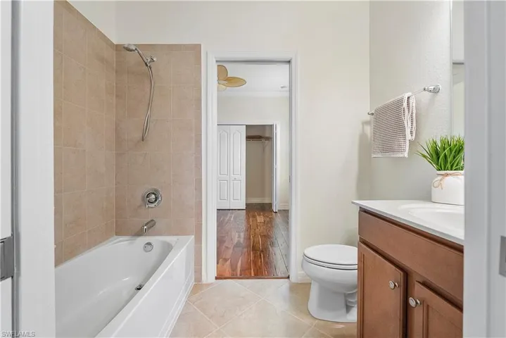 Full bath featuring vanity, baseboards, bathtub / shower combination, tile patterned floors, and toilet