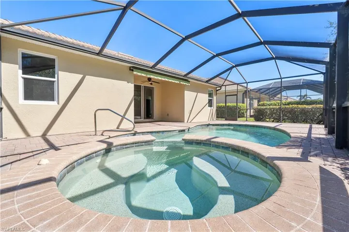 View of pool with a lanai, a heated pool with connected hot tub, a patio, and a ceiling fan