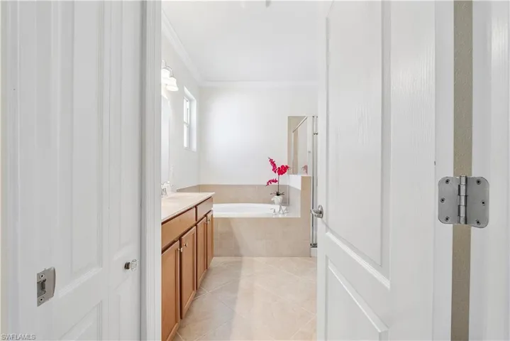 Full bathroom with tile patterned flooring, vanity, a garden tub, and ornamental molding