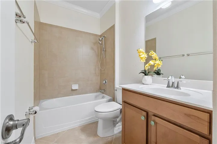 Full bathroom with toilet, ornamental molding, shower / bathing tub combination, tile patterned flooring, and vanity