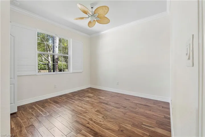 Spare room with crown molding, wood finished floors, baseboards, and ceiling fan