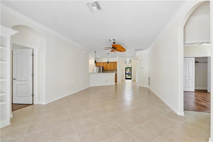 Unfurnished living room with crown molding, light tile patterned flooring, a ceiling fan, and visible vents