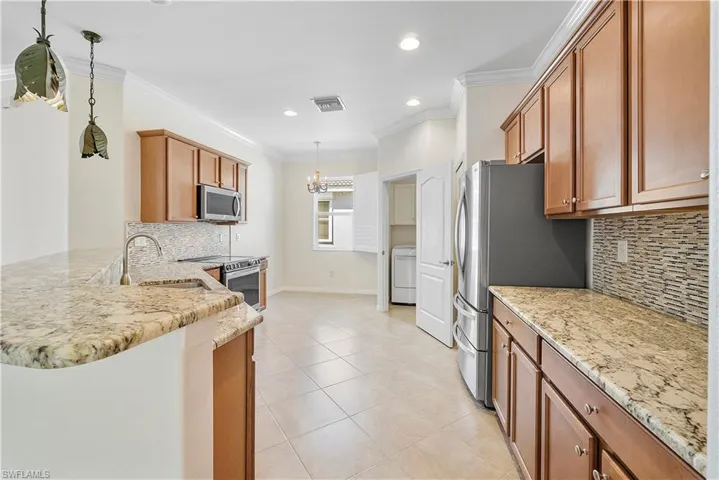 Kitchen featuring a raised breakfast bar , visible vents, ornamental molding, a sink, washer / clothes dryer, and appliances with stainless steel finishes