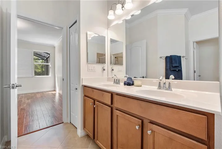 Bathroom with tile patterned floors, ornamental molding, double vanity, and a sink