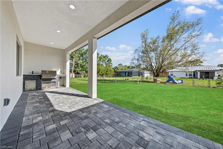 Fenced backyard with exterior kitchen and a patio
