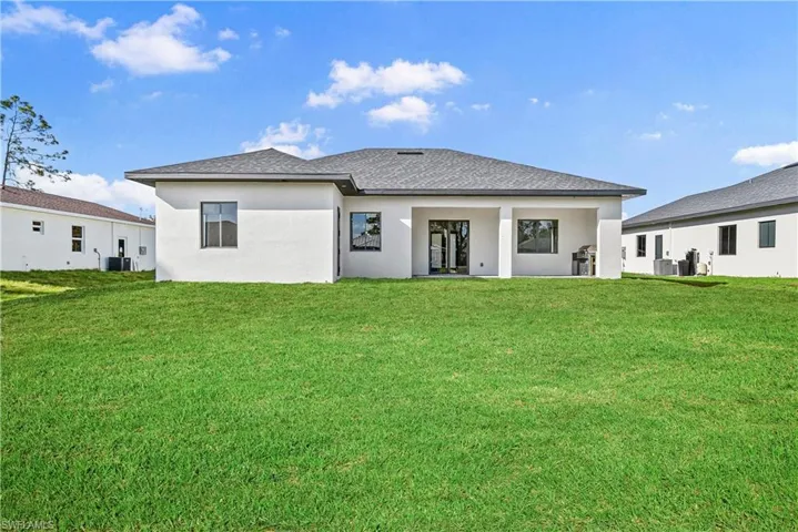 Back of house featuring a yard, a patio, and stucco siding