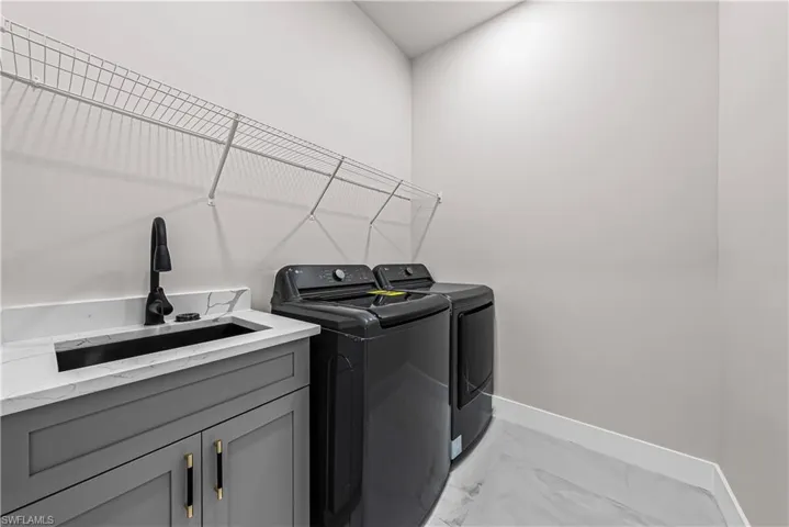 Laundry room with light marble finish flooring, separate washer and dryer, and cabinet space