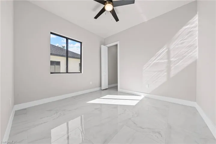 Unfurnished bedroom featuring light marble finish floors and ceiling fan