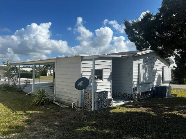 View of property exterior featuring a yard and a carport