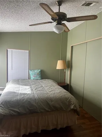 Bedroom featuring a textured ceiling, ceiling fan, dark wood-type flooring, and a closet