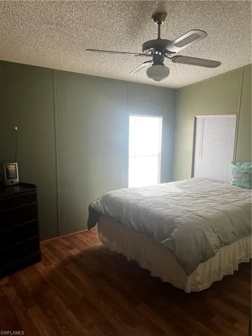 Bedroom with a textured ceiling, ceiling fan, and dark wood-type flooring