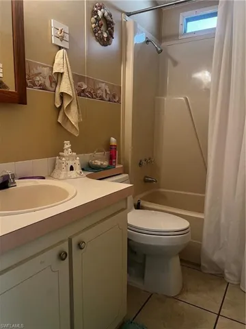 Bathroom with vanity, shower / tub combo with curtain, and light tile patterned floors