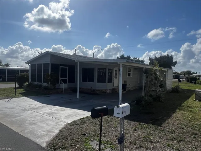 View of front of house featuring an attached carport, a sunroom, concrete driveway, and a patio area