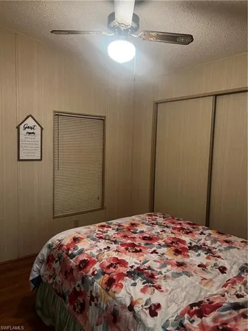 Bedroom featuring a textured ceiling, a ceiling fan, wood finished floors, and a closet