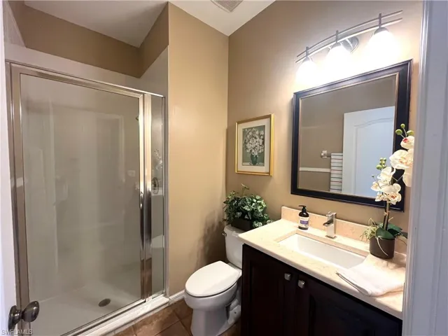 Full bath with vanity, a stall shower, and dark tile patterned flooring