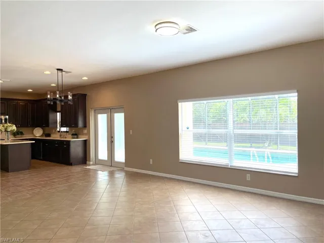 Kitchen with plenty of natural light, light tile patterned floors, dark wood finish cabinets, and open floor plan
