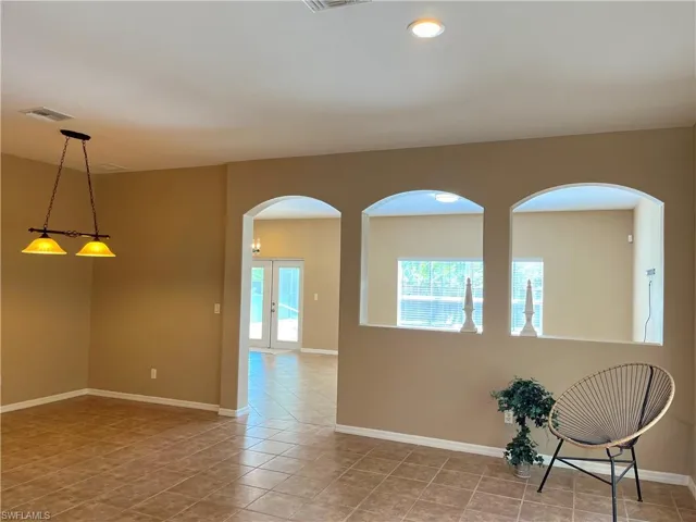 Unfurnished room with healthy amount of natural light, arched walkways, and light tile patterned floors