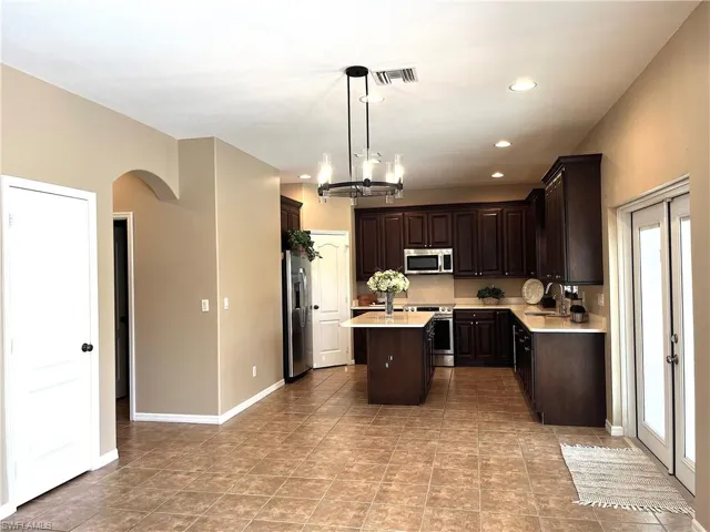 Kitchen with dark wood finish cabinets, a center island, stainless steel appliances, and hanging lights