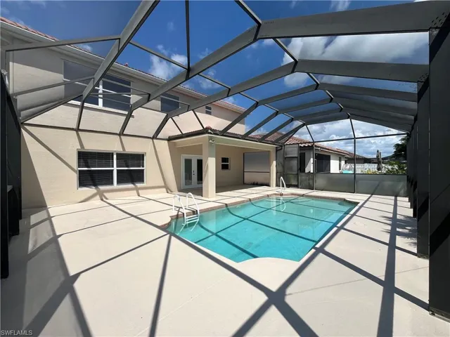 Outdoor pool with a patio area, a sunroom, glass enclosure, and french doors