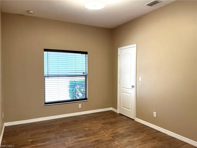 Unfurnished room with dark wood-style floors and baseboards
