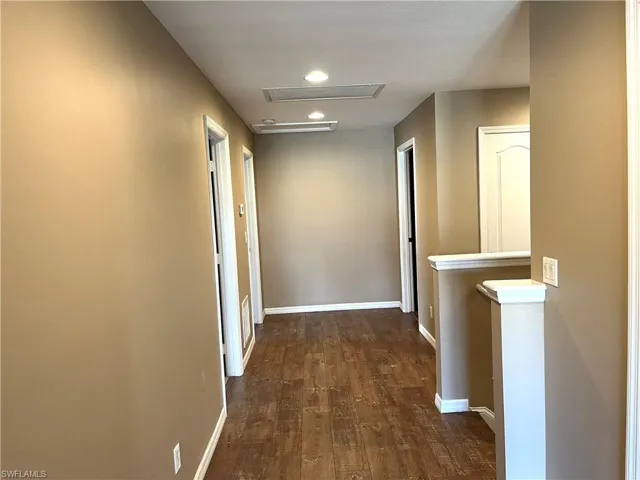 Corridor featuring dark wood-type flooring, recessed lighting, and an upstairs landing