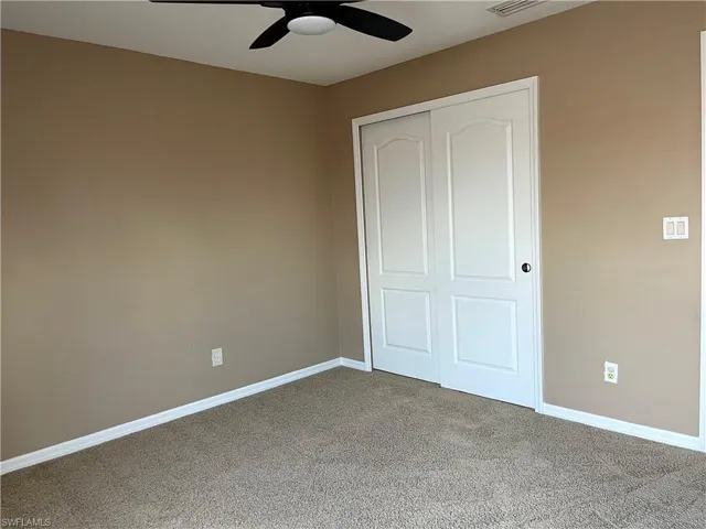 Unfurnished bedroom with carpet, a closet, and ceiling fan