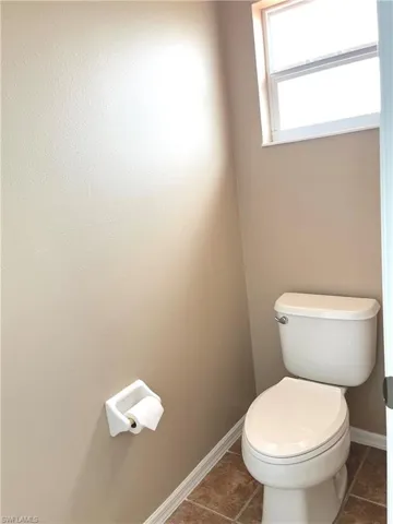 Bathroom with toilet and dark tile patterned flooring
