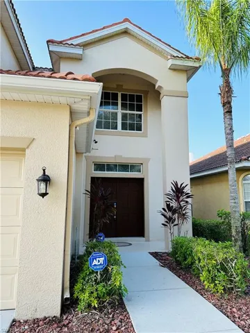 Doorway to property featuring stucco siding, a tile roof, and a garage