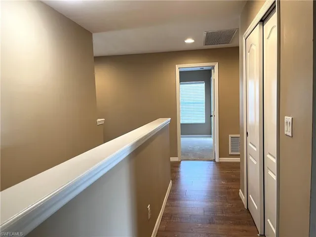 Corridor with an upstairs landing, dark wood-type flooring, and recessed lighting