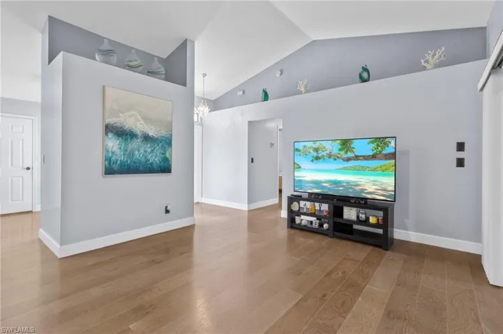 Living room featuring hardwood / wood-style floors, high vaulted ceiling, and an inviting chandelier